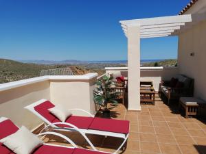 un patio con sedie rosse e bianche sul balcone di Exquisite modern 2-Bed House in El Pinar de Bedar a Bédar