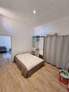 een slaapkamer met een bed en een houten vloer bij Mon Petit Patio - 4 chambres in Fourques