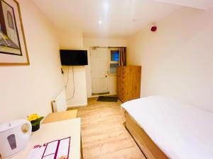 a bedroom with a bed and a desk and a television at White House Lodge in Cambridge