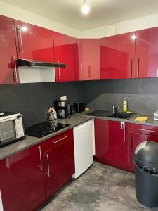 - une cuisine rouge et blanche avec des armoires rouges dans l'établissement Joli studio Hyper centre de Beauvais, à Beauvais