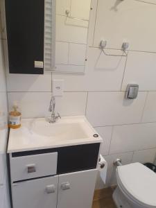 ein weißes Bad mit einem Waschbecken und einem WC in der Unterkunft Casa proxima a Praia do Rosa e Barra de Ibiraquera 2 quartos com ar condicionado in Imbituba