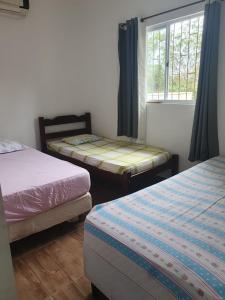 a bedroom with two twin beds and a window at Casa proxima a Praia do Rosa e Barra de Ibiraquera 2 quartos com ar condicionado in Imbituba