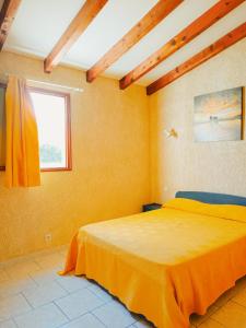 a bedroom with a bed with yellow walls and a window at Residence Maïna in Cargèse