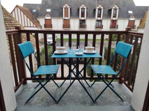 - Balcón con mesa azul y 2 sillas en APPT 4P - Manoirs 1 à la Mer Chez Claudette & Marc, en Courseulles-sur-Mer