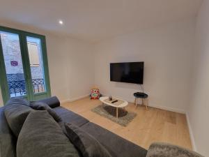 a living room with a couch and a flat screen tv at Mon Petit Patio - 4 chambres in Fourques