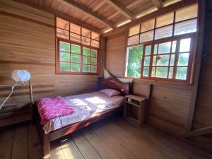 a small bedroom with a bed in a wooden cabin at Playa Tortuga in Puerto Misahuallí