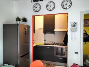 a kitchen with clocks on the wall and a refrigerator at Tre Continenti - Appartamento con parcheggio privato in Ronchi dei Legionari