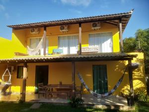 a yellow house with a table in front of it at Pousada Alto da Marina in Búzios