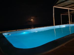 una piscina notturna con l'oceano sullo sfondo di Restaurante & Pousada Portal dos Ventos a Icapuí