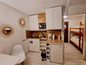 una pequeña cocina con armarios blancos y una litera en 100 m de la plage - Les Cigales de Mer - Studio Cabine - Parking en Le Grau-du-Roi