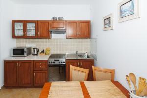 cocina con armarios de madera, mesa y fogones en Vila Helena - Apartmán Helena 3, en Ružomberok