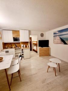 cocina con armarios blancos, mesa y sillas en 100 m de la plage - Les Cigales de Mer - Studio Cabine - Parking, en Le Grau-du-Roi