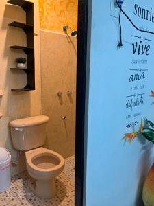 a bathroom with a toilet and a sign on the wall at Cuartos kukulcan in Valladolid