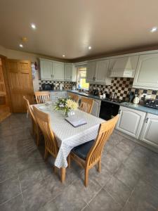 una cucina con tavolo e sedie e una cucina con armadietti bianchi di Beachview Cottage Co. Antrim a Cushendun