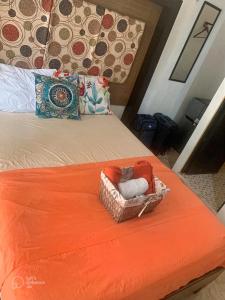 a bed with an orange blanket and a basket of towels at Cuartos kukulcan in Valladolid
