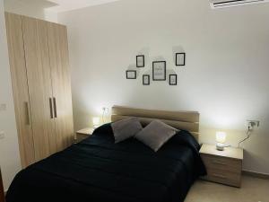 een slaapkamer met een zwart bed en foto's aan de muur bij New, Modern Ground Floor Apartment with Pool in Għajnsielem