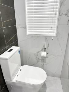 a white bathroom with a toilet and a window at Trafalgar Place in Auckland