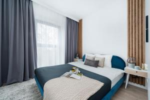 Un dormitorio con una cama grande y una ventana en Lake Club Apartments by LoftAffair en Mikołajki