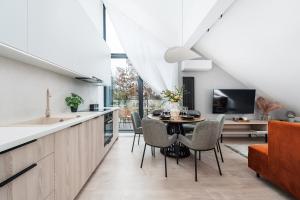 a kitchen and dining room with a table and chairs at Lake Club Apartments by LoftAffair in Mikołajki