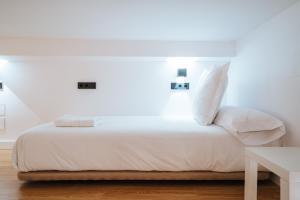 - un lit avec des draps et des oreillers blancs dans l'établissement apartamentos montevideo 6, à Séville