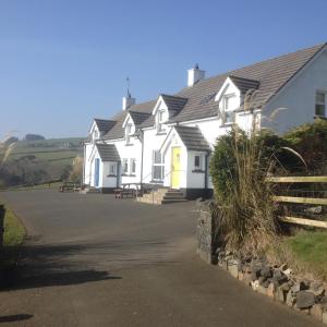 a white house with a yellow door on a road at Beachview Cottage Co. Antrim in Cushendun