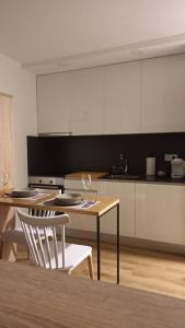 una cocina con mesa y 2 sillas y una cocina con armarios blancos. en IRLA, en Pontevedra