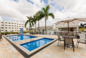 a swimming pool with a table and chairs and a building at Agua Marinha Campos in Campos dos Goytacazes