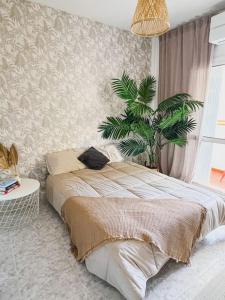 - une chambre avec un lit et une plante en pot dans l'établissement Apartamento moderno y acogedor cerca del mar, à Fuengirola