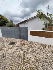 ein Haus mit einem Zaun und einer steinernen Einfahrt in der Unterkunft CASINHA DO RIO in Soure