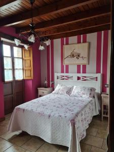 een slaapkamer met een bed met roze en witte strepen bij La Torruca in Oreña