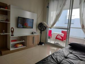 uma sala de estar com uma televisão, uma cama e uma janela em Lindo ap, mobiliado na praia do Novo Campeche em Florianópolis