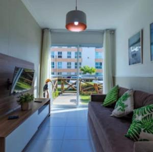 un salon avec un canapé et un balcon dans l'établissement flatmaravilha, à Porto de Galinhas