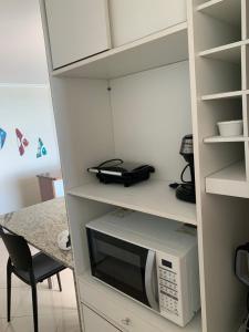 a kitchen with a microwave and a table at Porto Marina in Salvador