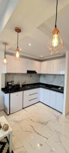 a kitchen with white cabinets and two lights at Luxueux Appartement DOWNTOWN RABAT in Rabat