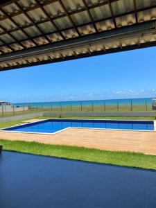 a swimming pool with the ocean in the background at Nosso Recanto in Porto de Sauipe