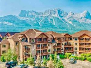 a large apartment building with mountains in the background at Mountain View 1 BR Condo With Gym & Hot-Tubs in Canmore