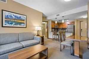 sala de estar con sofá, mesa y cocina en Mountain View 1 BR Condo With Gym & Hot-Tubs, en Canmore