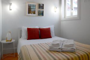 een wit bed met rode kussens en handdoeken erop bij Fabulous apartment by Douro River in Porto