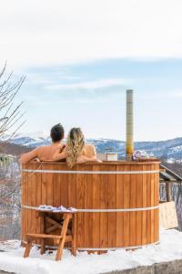 a couple sitting in a hot tub in the snow at Holiday Home Captain's Village in Šljivovica