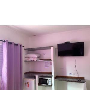 a small room with a tv and a microwave at Residencial Villa Nova SUITE in Boicucanga