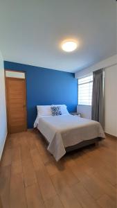 1 dormitorio con 1 cama con pared azul en Majhu Hostal, en Tacna