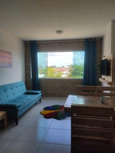 a living room with a blue couch and a large window at Flat JOÃO PESSOA JACUMÃ in Jacumã