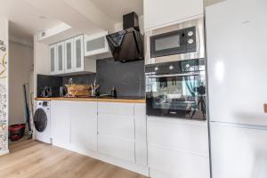 a kitchen with white cabinets and a microwave at Maison Althéa - Calme, Spa & Extérieur plein sud in Lempty