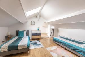 a bedroom with two beds and a clock on the wall at Maison Althéa - Calme, Spa & Extérieur plein sud in Lempty +36 photos