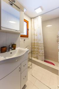 a white bathroom with a sink and a shower at Holiday Home Captain's Village in Šljivovica