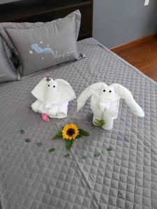 two towel animals on a bed with flowers at Nhà nguyên căn T Home BMT in Buon Ma Thuot