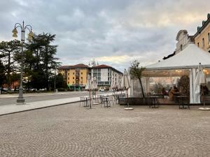 un groupe de tables et de parasols sur une rue de la ville dans l'établissement Dolada, meraviglia nel centro di Belluno, à Belluno