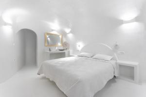 a white bedroom with a white bed and a mirror at Sun Naam Home Santorini with heated jacuzzi in Karterados