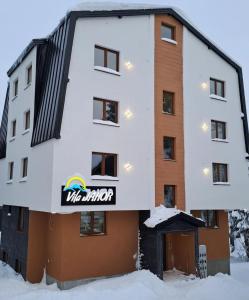 a building with a sign on it in the snow at Vila Jahor Apartman Miro in Jahorina