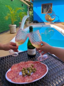 two people holding wine glasses and a plate of food at Vila Verde Chalés-Serro in Sêrro